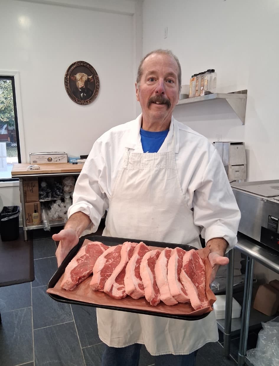 Marty in his butcher’s apron holding a tray of fresh-cut steaks