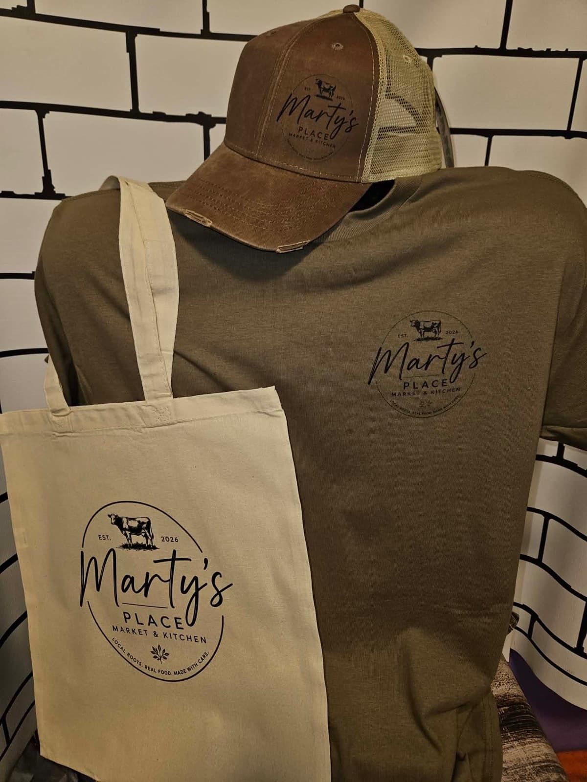 A Marty’s Place hat, tee and tote bag displayed with the logo
